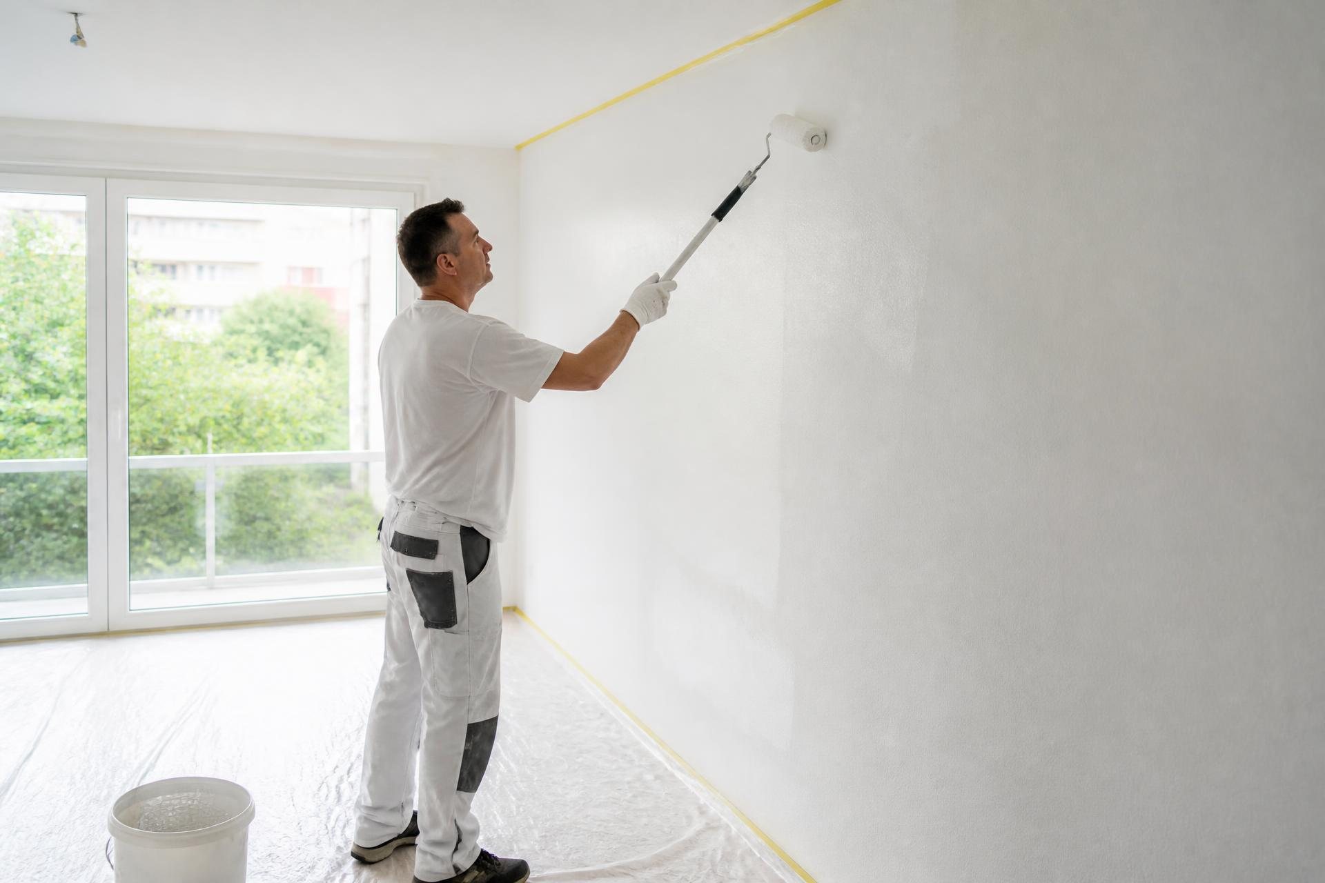 Maler von ARA streicht mit Rolle eine Wohnzimmerwand in einer Schweizer Wohnung